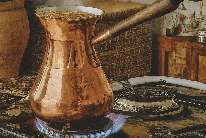 Cafetera de cobre tradicional calentándose en una estufa de gas